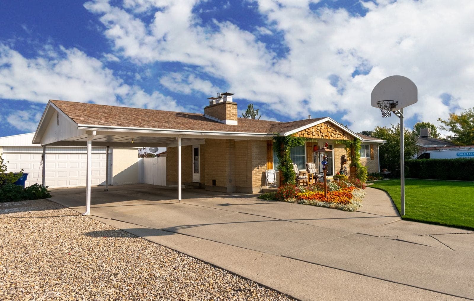 A ranch house with a brick chimney and a carport